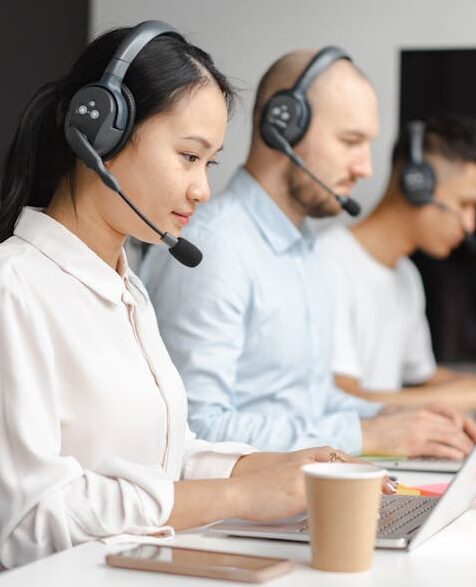 Customer service agents efficiently handle calls using laptops and headsets in a modern office.